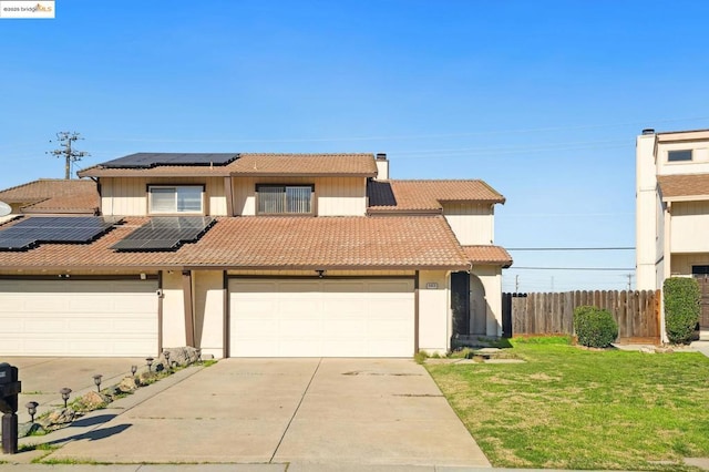 view of front of property with a garage, a front yard, and solar panels