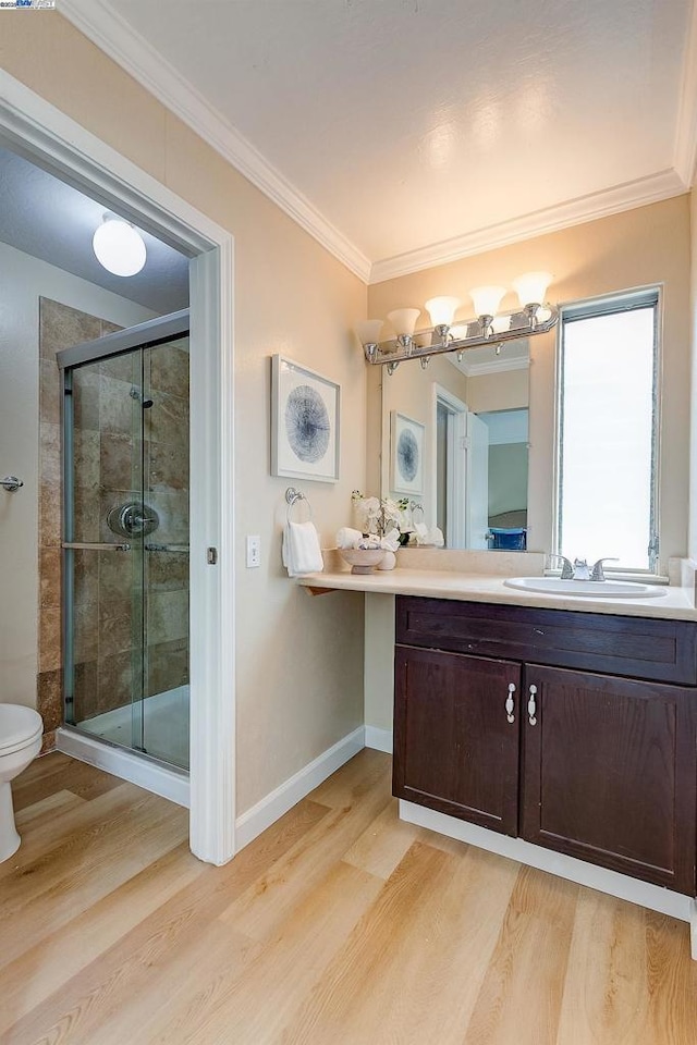 bathroom with toilet, crown molding, vanity, a shower with door, and hardwood / wood-style floors