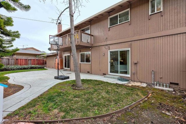 rear view of property with a patio, a balcony, and a yard