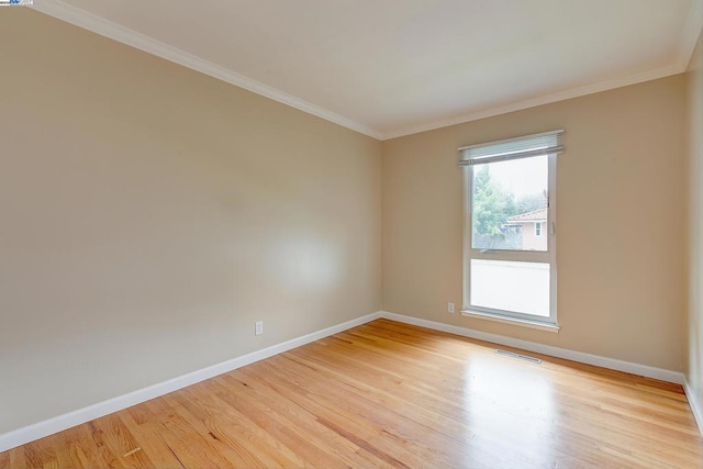 spare room featuring ornamental molding and light hardwood / wood-style flooring