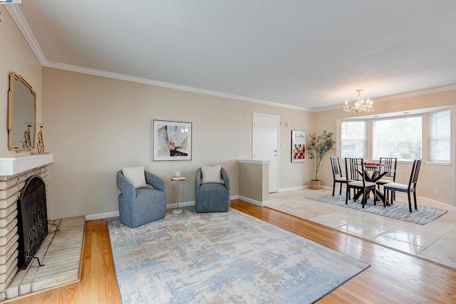 living area featuring a brick fireplace, light hardwood / wood-style flooring, ornamental molding, and a chandelier