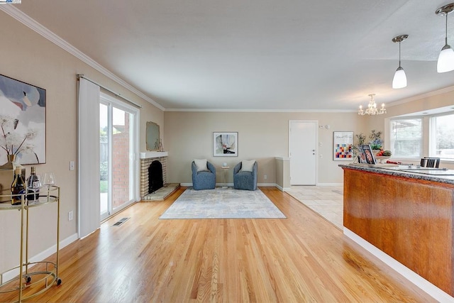 interior space with an inviting chandelier, ornamental molding, a fireplace, and light wood-type flooring