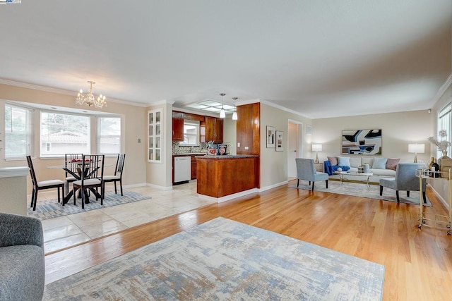 living room with an inviting chandelier, ornamental molding, and light wood-type flooring