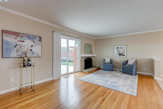 living area featuring hardwood / wood-style flooring, ornamental molding, and a brick fireplace