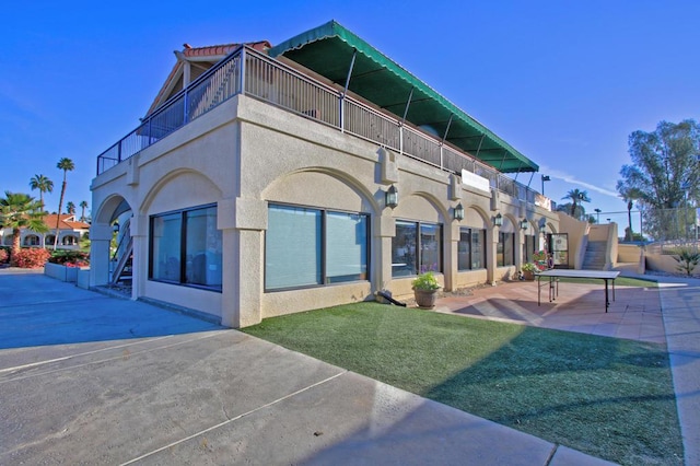 exterior space featuring a patio, a balcony, and a lawn