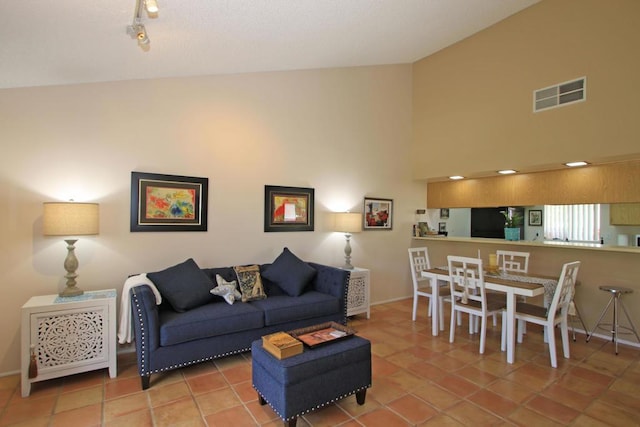 tiled living room featuring track lighting and high vaulted ceiling