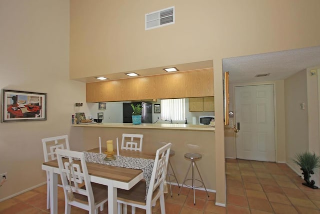 dining room featuring tile patterned flooring and a high ceiling