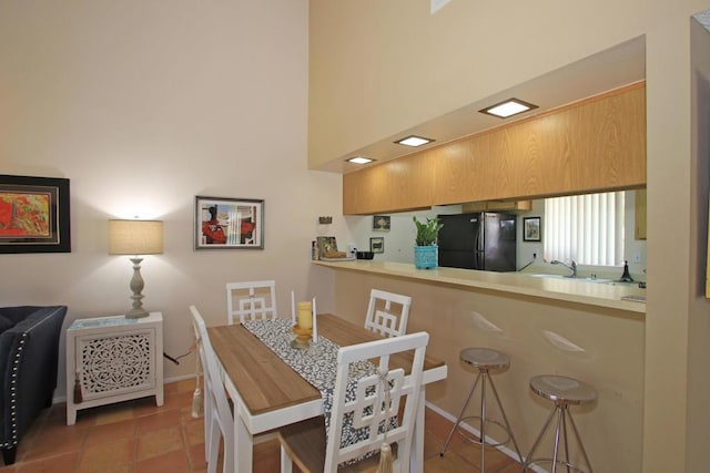 tiled dining space with a high ceiling and sink