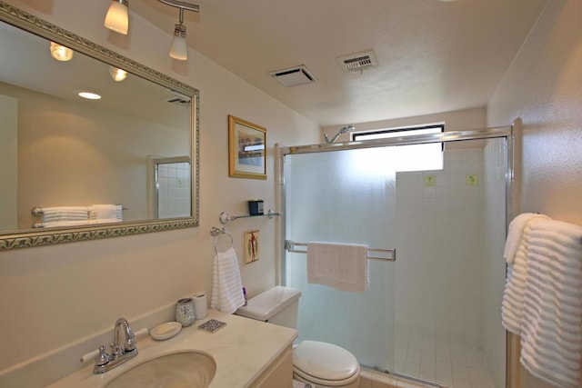 bathroom featuring vanity, a shower with shower door, and toilet