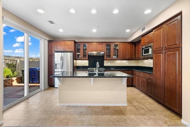 kitchen with a kitchen island with sink, sink, stainless steel appliances, and a kitchen bar