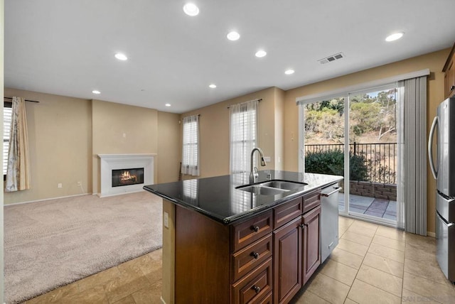 kitchen featuring a kitchen island with sink, sink, light carpet, and stainless steel appliances