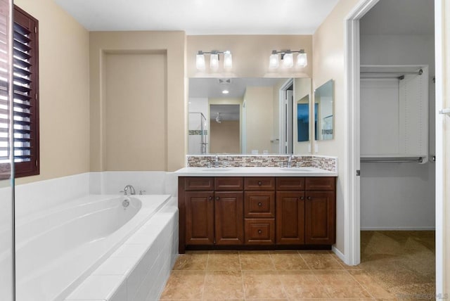 bathroom featuring vanity, backsplash, tile patterned flooring, and tiled bath