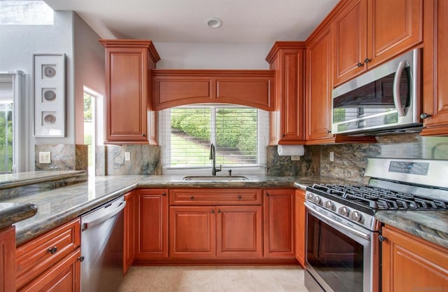 kitchen with dark stone countertops, sink, tasteful backsplash, and appliances with stainless steel finishes