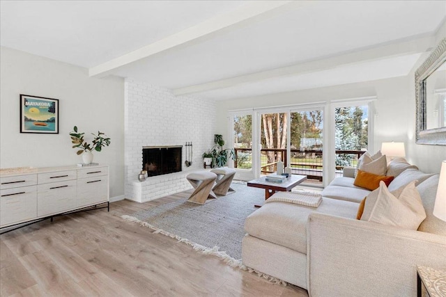 living room featuring beamed ceiling, a fireplace, and light wood-type flooring