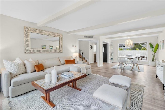 living room featuring beamed ceiling, light hardwood / wood-style floors, and a notable chandelier