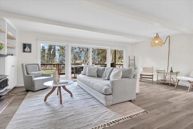 living room featuring hardwood / wood-style floors, beam ceiling, and a wood stove