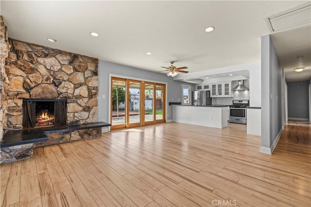 unfurnished living room featuring ceiling fan, light wood-type flooring, and a fireplace