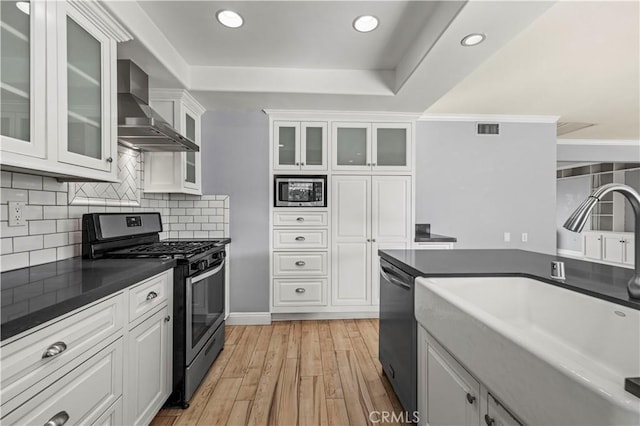 kitchen featuring stainless steel appliances, sink, wall chimney range hood, and white cabinets