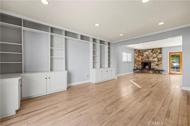 unfurnished living room with crown molding, a fireplace, and light wood-type flooring