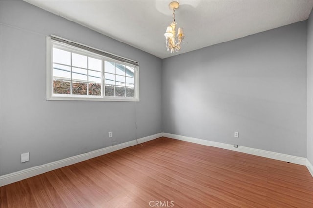 spare room featuring an inviting chandelier and wood-type flooring