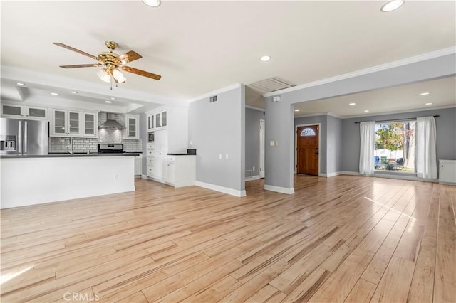 unfurnished living room featuring ceiling fan, ornamental molding, and light wood-type flooring