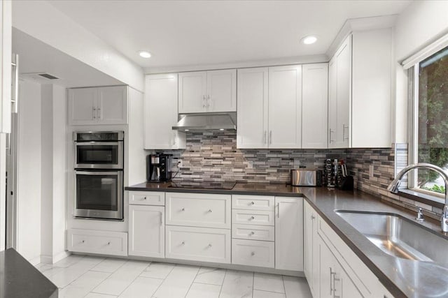 kitchen featuring black electric cooktop, stainless steel double oven, sink, and white cabinets