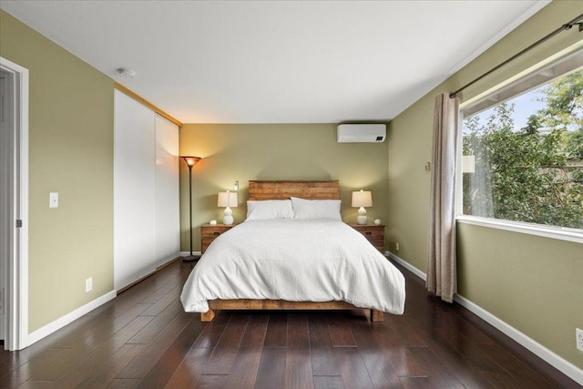 bedroom with a wall mounted air conditioner and dark hardwood / wood-style floors