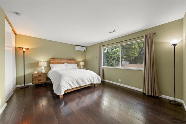 bedroom with dark hardwood / wood-style flooring and a wall unit AC