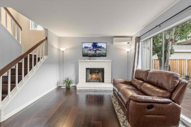 living room with dark wood-type flooring, a wall mounted air conditioner, a fireplace, and a wealth of natural light