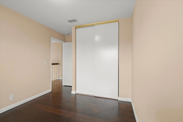 unfurnished bedroom featuring dark wood-type flooring and a closet