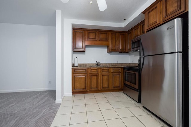 kitchen with sink, light tile patterned floors, ceiling fan, stainless steel appliances, and light stone countertops