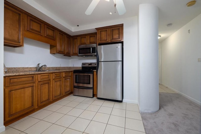 kitchen with sink, light stone counters, light tile patterned floors, ceiling fan, and stainless steel appliances