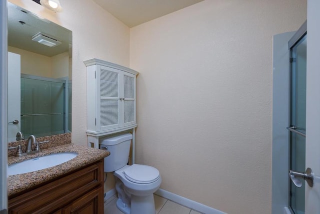 bathroom with a shower with door, vanity, tile patterned floors, and toilet