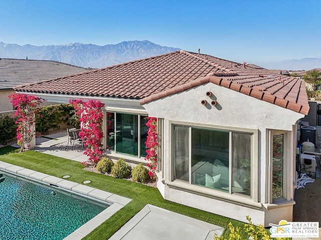 back of property featuring a yard, a mountain view, and a patio area