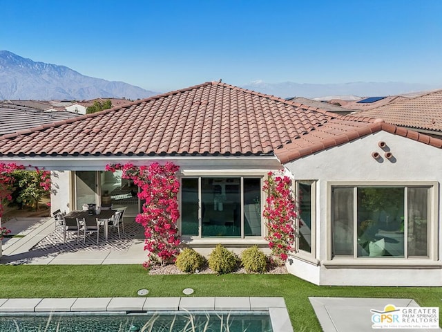 back of house featuring a mountain view, a lawn, and a patio