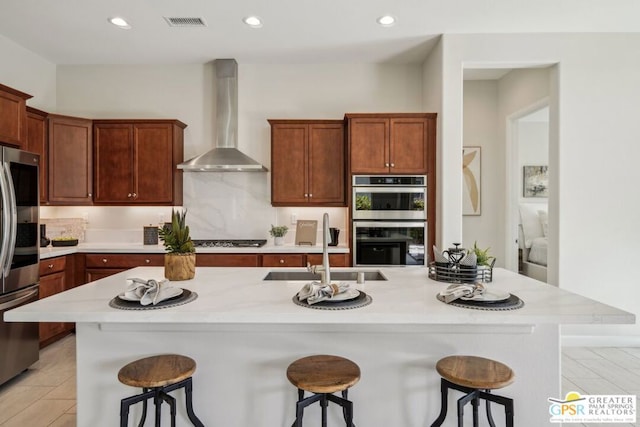 kitchen featuring appliances with stainless steel finishes, sink, a breakfast bar area, and wall chimney exhaust hood