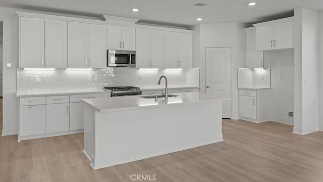 kitchen with sink, stainless steel appliances, an island with sink, and white cabinets