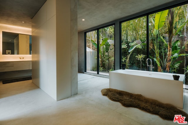 bathroom featuring a bathing tub, sink, concrete floors, and a wall of windows