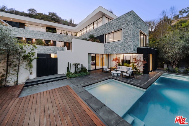 back of house with a pool side deck, an outdoor living space, and a patio