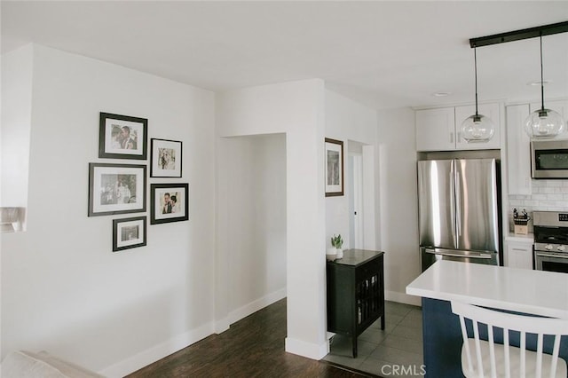 kitchen with pendant lighting, white cabinets, decorative backsplash, stainless steel appliances, and dark wood-type flooring