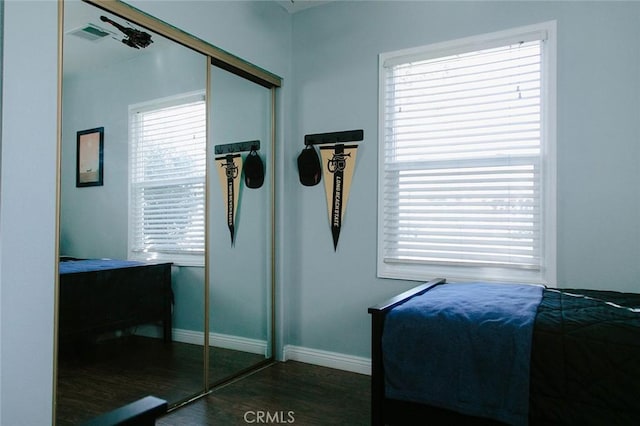 bedroom featuring multiple windows, a closet, and dark hardwood / wood-style floors