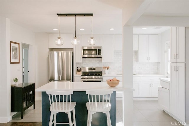 kitchen featuring backsplash, stainless steel appliances, a kitchen island, and white cabinets