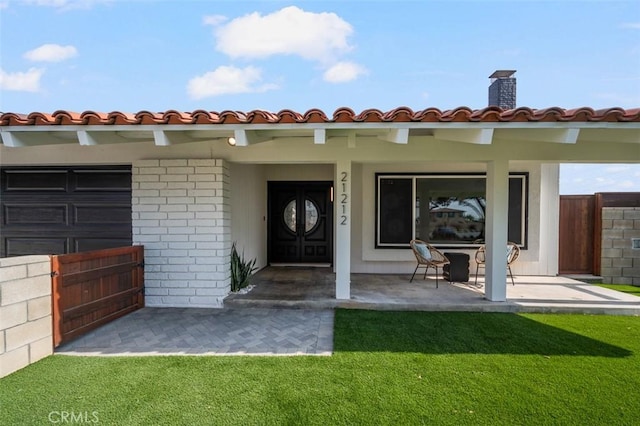 view of exterior entry with a patio and a yard