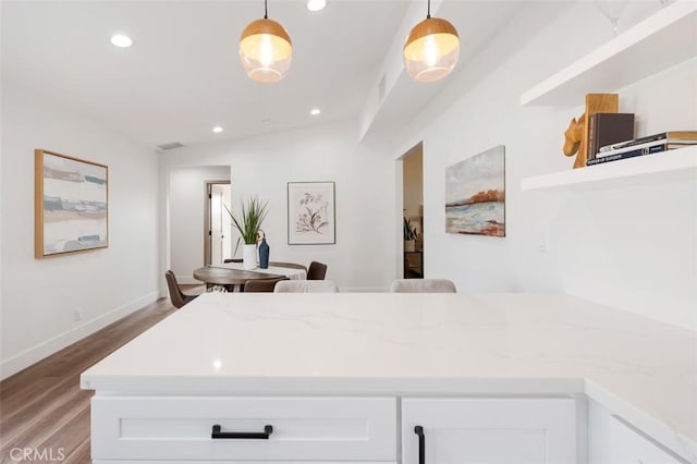 interior space featuring lofted ceiling, hardwood / wood-style floors, white cabinets, and decorative light fixtures