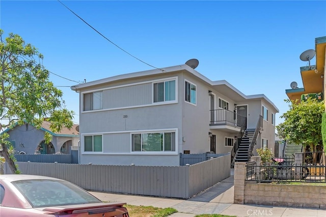 view of front of home with a fenced front yard, stairs, and stucco siding