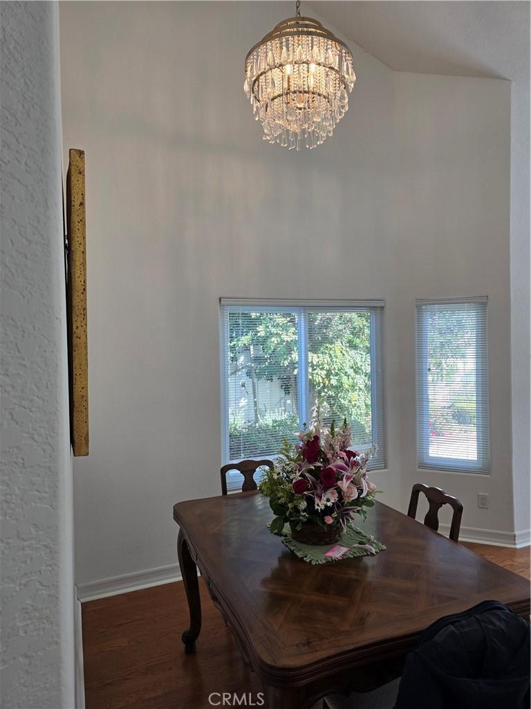 dining room featuring a towering ceiling, wood-type flooring, and a notable chandelier