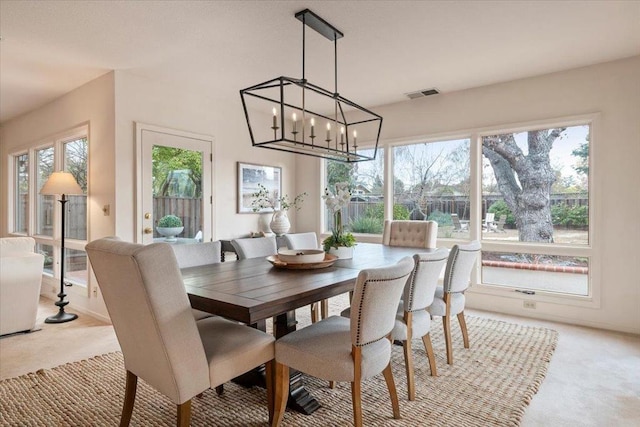 carpeted dining room with a notable chandelier