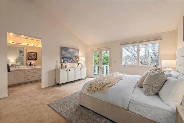 carpeted bedroom with sink, ensuite bath, access to outside, and high vaulted ceiling