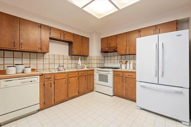 kitchen with white appliances, sink, and backsplash