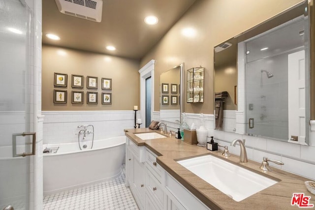 bathroom featuring independent shower and bath, vanity, tile walls, and tile patterned floors